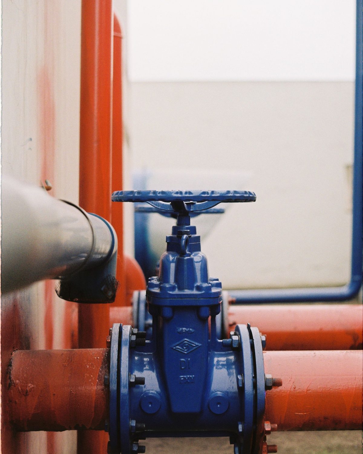 Blue-handled gate valve on a run of red pipes